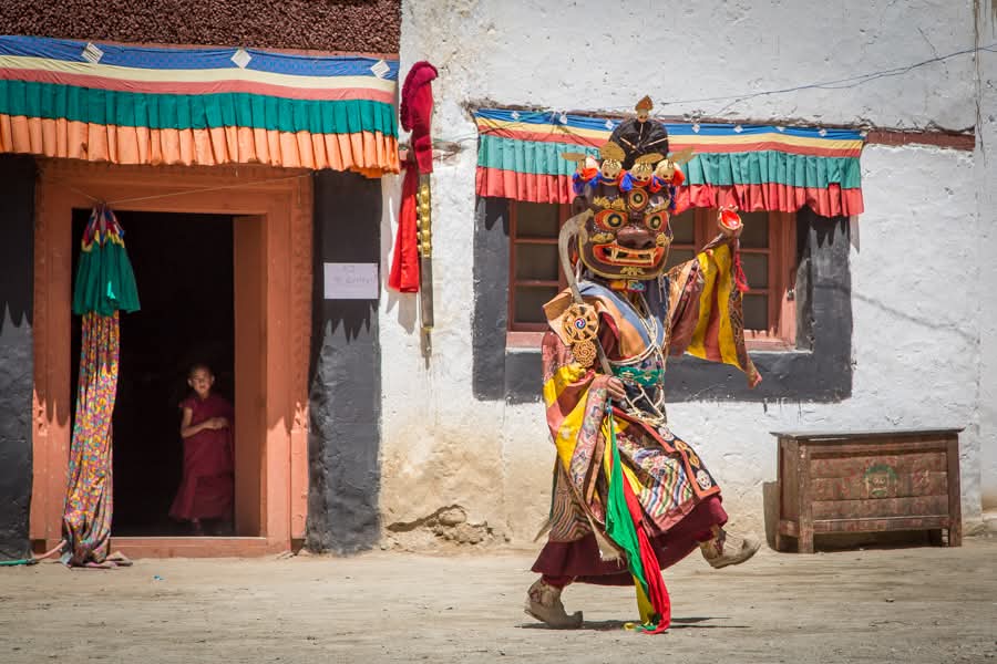 Danse masquée Cham lors d'un festival monastique avec un jeune moine observant